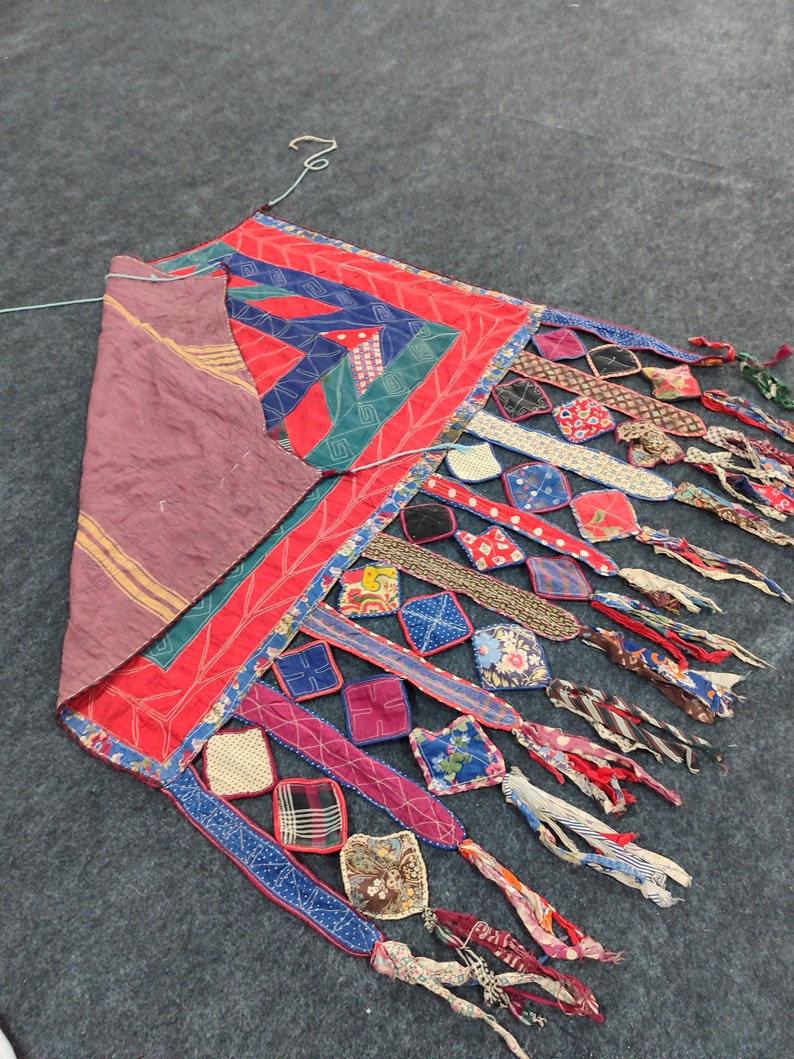 May include: A colorful patchwork quilt with a geometric design and fringe. The quilt is made of various fabrics in shades of red, blue, green, and brown.
