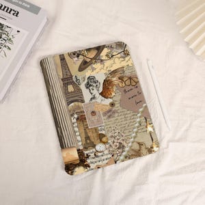 Könnte beinhalten: Eine iPad-Hülle im Stil einer Vintage-Collage. Die Hülle zeigt Bilder vom Eiffelturm, einer Uhr, einem Vogel und einer Perlenkette. Der Text "There is more to love" ist ebenfalls enthalten.