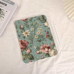 May include: A blue and green floral iPad case with a white background. The case features a variety of pink and white flowers with green leaves.
