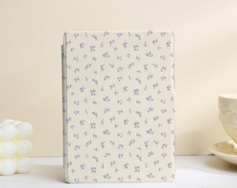 May include: A rectangular electronic reader case featuring a cream-coloured background with a repeating pattern of small, light blue floral blossoms and tiny green leaves distributed evenly across the entire surface of the protective cover.