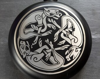 May include: Black metal flask with a silver Celtic knot design featuring two intertwined animals.