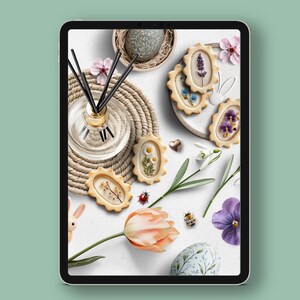 May include: A white background with a variety of spring-themed decorations, including a floral-patterned Easter egg, a nest with a speckled egg, a bouquet of white snowdrops, a pink tulip, a small bee, a glass bottle with black diffuser sticks, a brown woven mat, and several cookies decorated with pressed flowers.