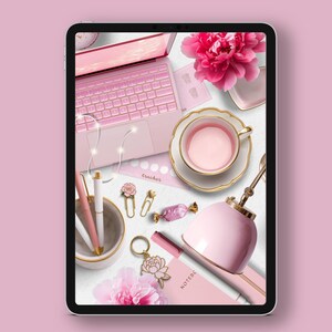 May include: A flat lay of a pink laptop, a pink teacup and saucer, a pink lamp, a pink notebook, and other pink office supplies on a white surface.