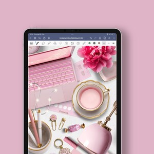 May include: A pink laptop computer with a pink keyboard and a white trackpad. The laptop is open and there are several pink and gold accessories on the table, including a teacup, a flower, and a pen.