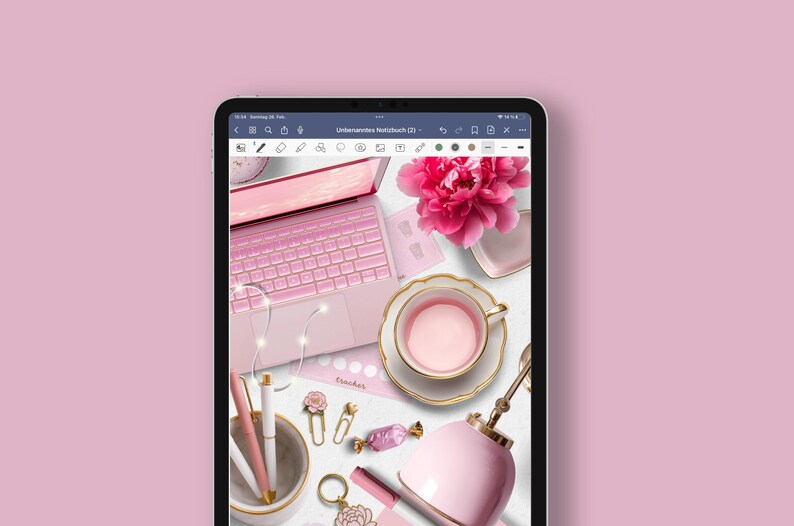 May include: A pink laptop computer with a pink keyboard and a white trackpad. The laptop is open and there are several pink and gold accessories on the table, including a teacup, a flower, and a pen.