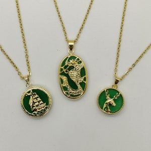 May include: Three gold necklaces with green jade pendants. The pendants feature a dragon, a ship, and a deer.