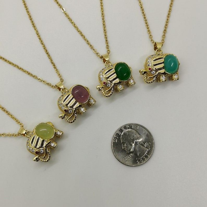 May include: Four gold elephant necklaces with clear crystal accents and different colored gemstone inlays. The gemstones are green, pink, and yellow.