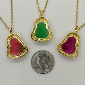 May include: Three gold necklaces with pendants shaped like the Buddha. The pendants are made of jade and come in green, pink, and purple.