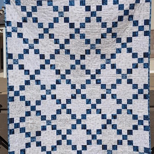 May include: A blue and white quilt with a checkered pattern. The quilt is made of fabric with a handwritten script design.
