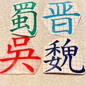 May include: Four colorful vinyl decals with Chinese characters. The characters are in green, blue, red, and navy blue. Each decal is a different shape, with a grid pattern visible behind the characters.