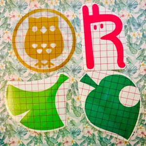 May include: Four vinyl stickers featuring characters from the Animal Crossing video game series. The stickers are on a white gridded background. The stickers are of an owl, a leaf, a leaf with a hole in it, and a red character with a long neck.