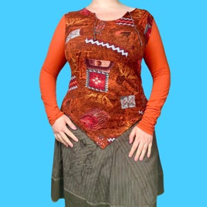 May include: A brown and orange long-sleeved shirt with a geometric print. The shirt has a V-neck and a long, flowing skirt.
