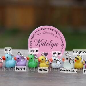 May include: Ten colorful rubber duck charms with silver jump rings. The ducks are pink, blue, purple, green, yellow, white, glow in the dark, sunglasses, and flamingo.