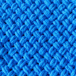 May include: A close-up of a blue knitted fabric with a textured, woven pattern.