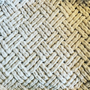 May include: A cream-coloured knitted throw blanket with a woven chevron pattern.