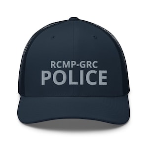 May include: Navy blue trucker hat with a mesh back and a curved brim. The front of the hat features the embroidered text "RCMP-GRC POLICE" in white block letters. A classic and functional accessory.