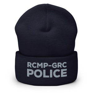 May include: A navy blue beanie with a white embroidered logo that reads "RCMP-GRC POLICE".