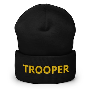 以下が含まれることがあります： カフに金色の刺繍で「TROOPER」と刺繍された黒いビーニー