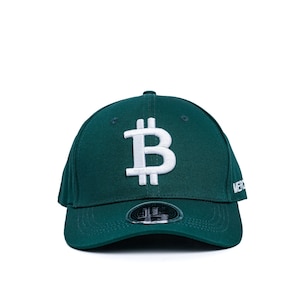 May include: A dark green baseball cap with a white embroidered Bitcoin symbol on the front. The cap has a black adjustable strap and a white embroidered "MERCH" on the side.
