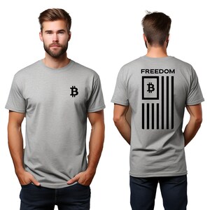 May include: A light gray t-shirt featuring a black Bitcoin symbol on the front and a stylized American flag design on the back. The flag design incorporates the Bitcoin symbol and the word "FREEDOM" at the top.
