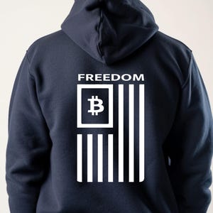 May include: A navy blue hoodie with a white graphic of an American flag with a Bitcoin symbol in the top left corner. The text "FREEDOM" is above the flag.