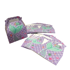 Puede incluir: Un montón de cajas de regalo para fiestas de color morado y verde con temática de cola de sirena. Las cajas están hechas de cartón y tienen un asa recortada. Las cajas están decoradas con una cola de sirena, conchas marinas y algas marinas.
