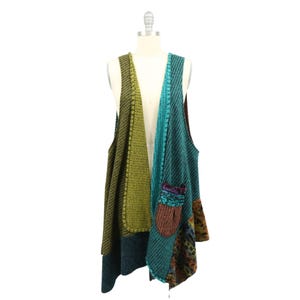 Puede incluir: Un chaleco sin mangas con un diseño de patchwork que presenta varias texturas y colores de punto. El lado izquierdo es de color verde oliva, mientras que el derecho muestra patrones en azul verdoso, azul y marrón con un bolsillo visible.