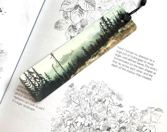 Aluminum double-sided bookmark with moody forest art print on one side and text on the other.
