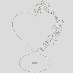 May include: A laser cut wooden heart-shaped frame with a decorative floral design and a small round base. The frame is perfect for displaying photos or other small items.