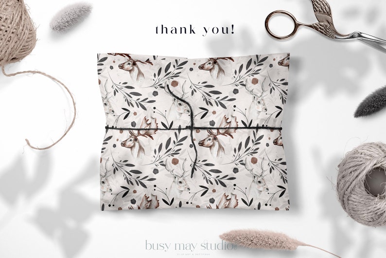 May include: A white gift bag with a brown and black deer and floral pattern. The bag is tied with a black string and the words "thank you!" are written in black above the bag.