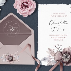 Puede incluir: Una invitaci&oacute;n de boda con un dise&ntilde;o floral de acuarela en tonos grises y rosas. La invitaci&oacute;n es para Charlotte y James, y establece la fecha y hora de la boda como el viernes 12 de junio a las 2 PM. La ubicaci&oacute;n es 15 Place Vendome, 75001 Par&iacute;s. La invitaci&oacute;n est&aacute; impresa en papel texturizado con un borde desgarrado.