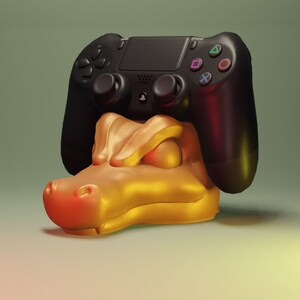 Może przedstawiać: Czarny kontroler PlayStation 4 spoczywa na złotym stojaku w kształcie aligatora. Kontroler ma przyciski w różnych kolorach i symbole. Stojak ma gładkie, błyszczące wykończenie.
