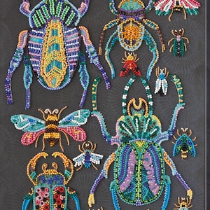 Può includere: Primo piano di un'opera d'arte realizzata con perline che presenta vari insetti colorati, tra cui scarabei, farfalle e api. Gli insetti sono disposti in uno schema simmetrico su uno sfondo nero.