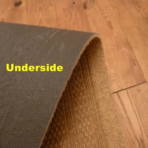 May include: A close-up of the underside of a rug, showing a brown, textured backing and a beige, patterned top. The text "Underside" is visible in yellow.