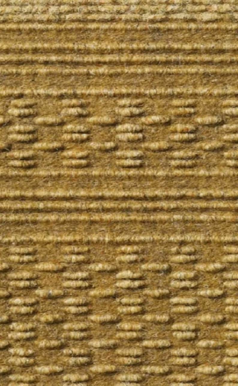 May include: Close-up of a textured, woven fabric in a light brown color. The fabric has a subtle pattern of small, raised bumps.