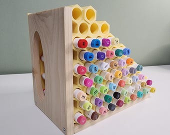 May include: A wooden hexagonal marker storage rack with a honeycomb design. The rack is filled with colorful markers, each with a different number.
