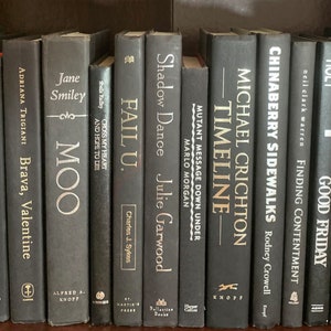 Puede incluir: Una estanter&iacute;a llena de libros negros y blancos con letras doradas. Los t&iacute;tulos de los libros incluyen "Gemba Kaizen", "Spin Masters", "Fail U", "Timeline", "Chinaberry Sidewalks", "Rwanda, Inc.", "The Case for Goliath" y "Final Truth".