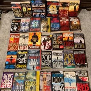May include: A collection of James Patterson novels, featuring titles like "Cross," "Alex Cross," and "Mary, Mary." The books have colorful covers with various designs and text. The books are arranged on a surface.