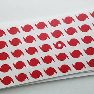 May include: A sheet of red hurricane stickers with one sticker missing from the center.