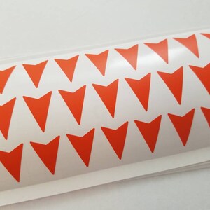 May include: A sheet of orange arrow stickers on a white background. The arrows are arranged in a repeating pattern.