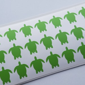 May include: A sheet of white paper with multiple green turtle silhouettes arranged in rows. The turtles are all facing the same direction.
