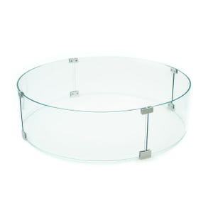 May include: A clear, circular glass fire pit wind guard. The curved glass panels are held together by silver-colored metal connectors. The guard is designed to encircle a fire pit, providing protection from wind.