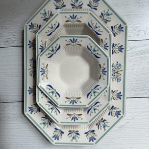 May include: A set of three octagonal ceramic plates with a floral design in blue, teal, and brown on a white background. The plates are arranged in a nested configuration, with a teal border.