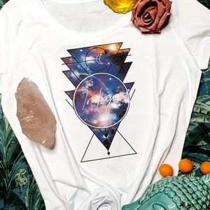May include: White t-shirt with a galaxy print and the word "Indigo" in a circle. The design features geometric shapes and a crescent moon.