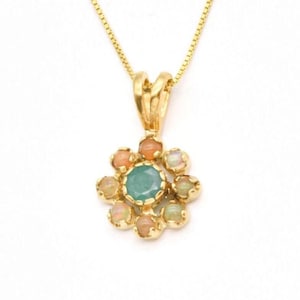 May include: A gold necklace with a pendant featuring a green emerald surrounded by smaller pink and white opals.