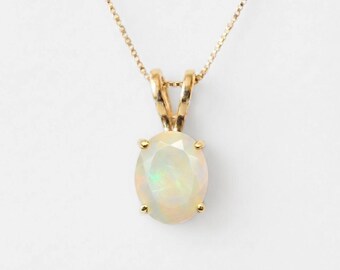 May include: A gold necklace featuring an oval-shaped opal pendant with a faceted surface. The opal displays iridescent flashes of color and is held by a four-prong gold setting. The pendant hangs from a delicate gold box chain.