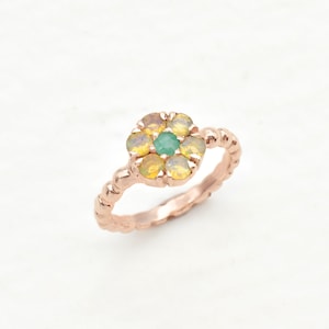 May include: A rose gold ring with a cluster of yellow and green gemstones set in a flower shape.