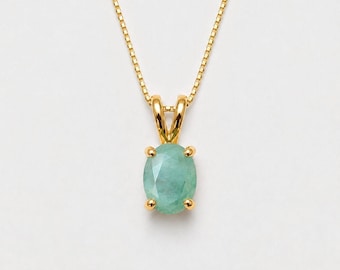 May include: A gold necklace featuring a delicate box chain and a pendant with an oval-cut, light green gemstone held in a four-prong setting. The pendant is suspended from a simple gold bail, showcasing a polished finish on the metal components.