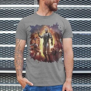 May include: A heather grey t-shirt with a graphic print of a scene from the movie Robocop. The graphic features Robocop standing in the middle of the scene with other characters from the movie surrounding him.