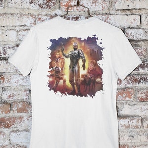 May include: White t-shirt with a graphic print of a silver robot character from the movie Robocop. The robot is standing in front of a cityscape with other characters in the background.